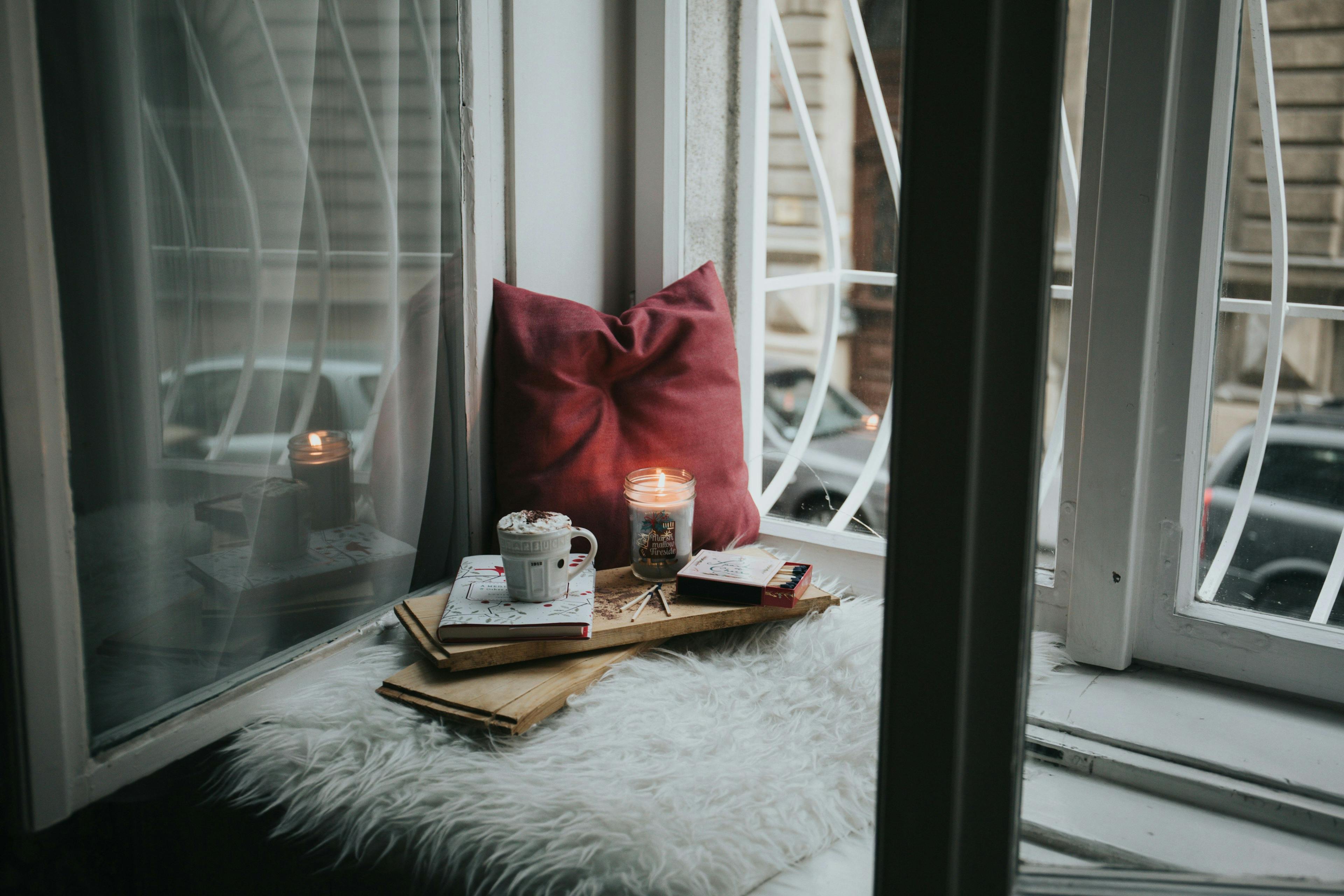 a window sill with a tray of books and a candle on it